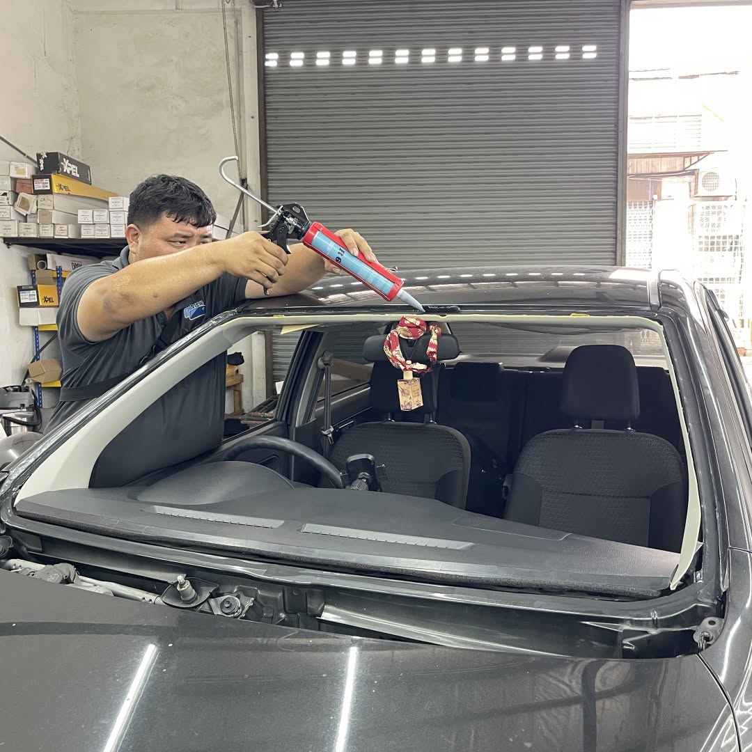 Top View technician applying adhesive during a Perodua Bezza windscreen replacement